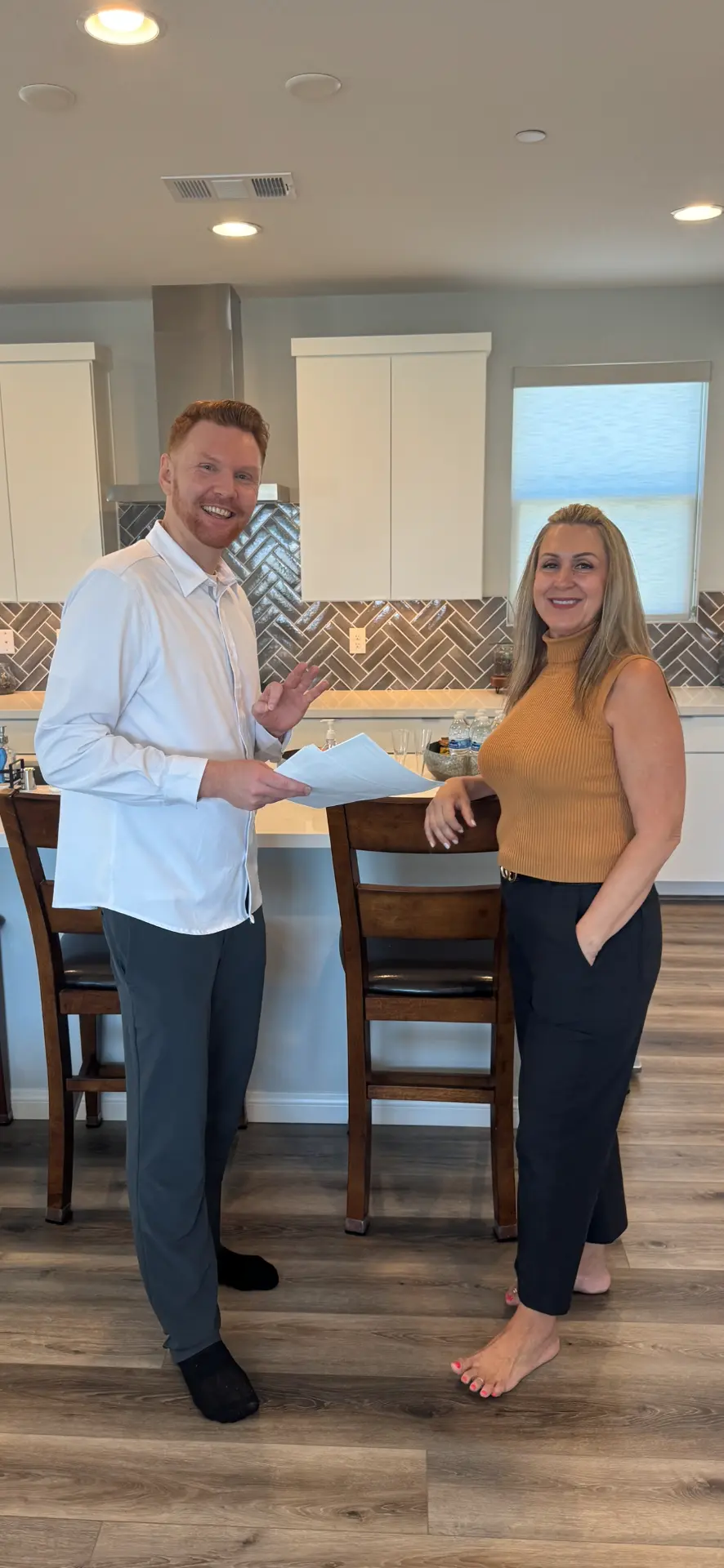 Ashley Bell handing signed closing paperwork to a happy buyer in a new Las Vegas kitchen